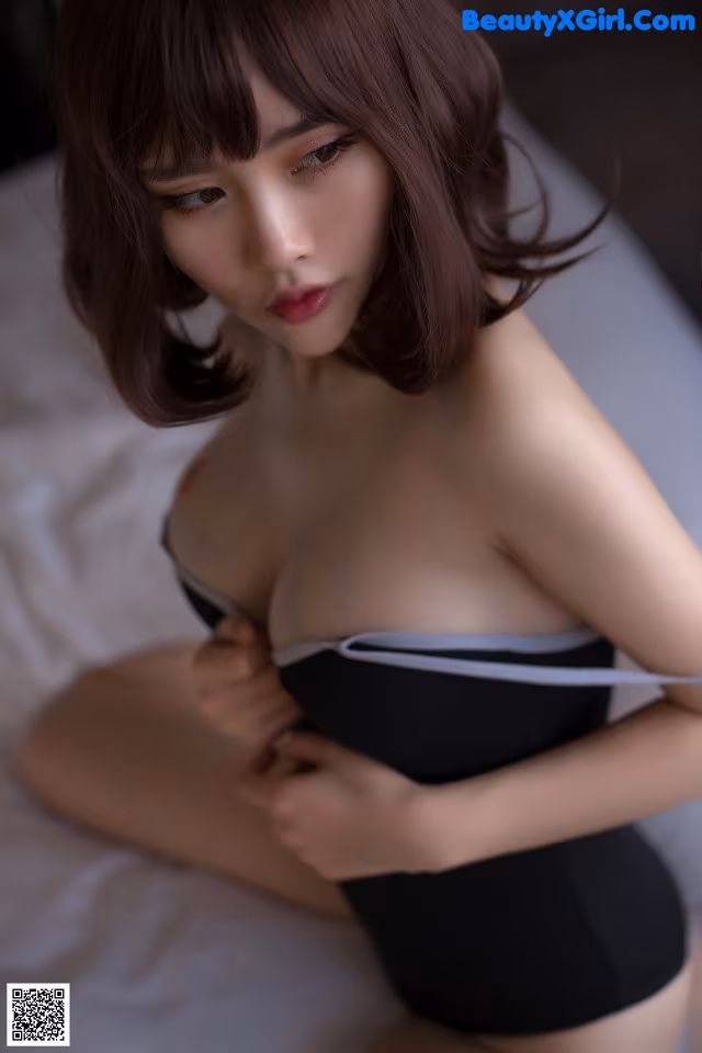 A woman in a black bodysuit sitting on a bed.
