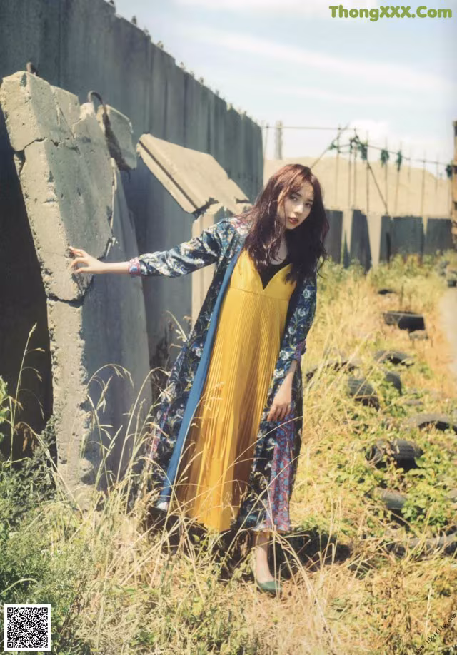 A woman in a yellow dress standing in a field.