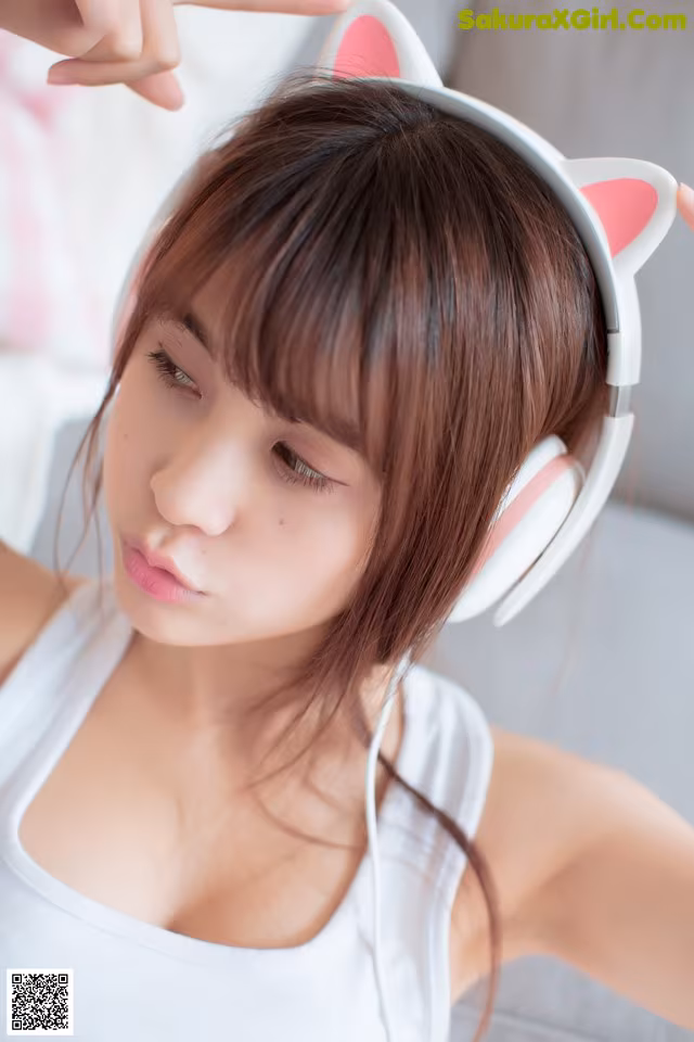A woman wearing a pair of white headphones with pink ears.