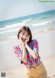 A woman standing on a beach next to the ocean.