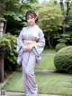 A woman in a kimono standing in a garden.