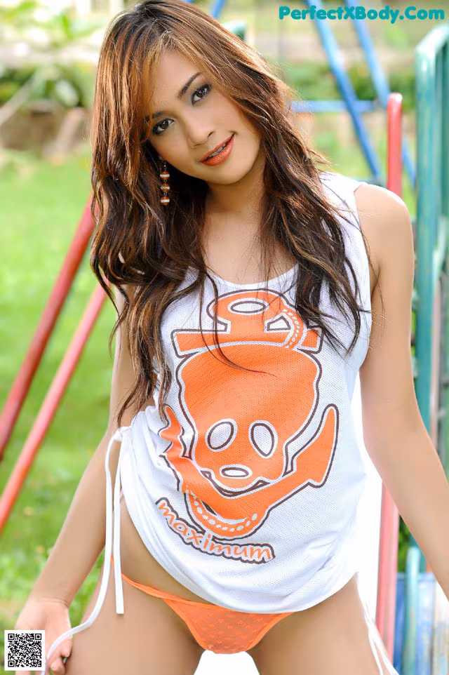 A woman in a white tank top and orange bikini posing for a picture.