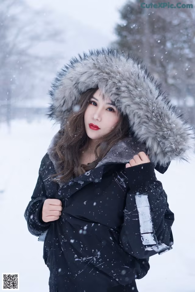 A woman in a black jacket with a fur hood in the snow.
