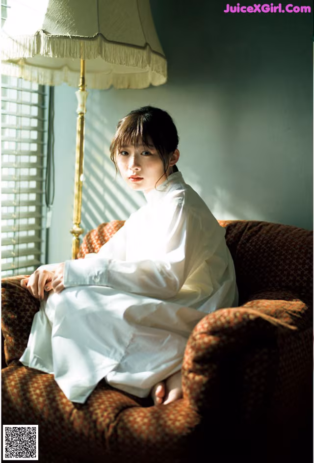 A woman sitting on a chair in front of a lamp.