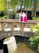 A woman in a pink skirt standing on a stone bridge.