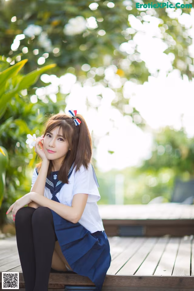 A woman in a school uniform sitting on a wooden bench.