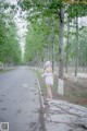 A woman in a white dress standing in the middle of a road.