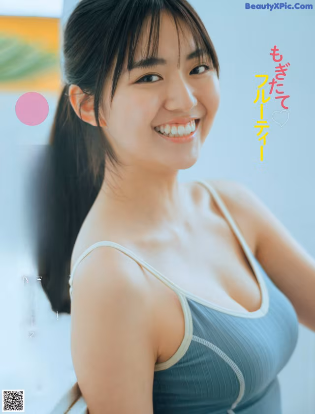 A woman in a blue tank top smiles at the camera.