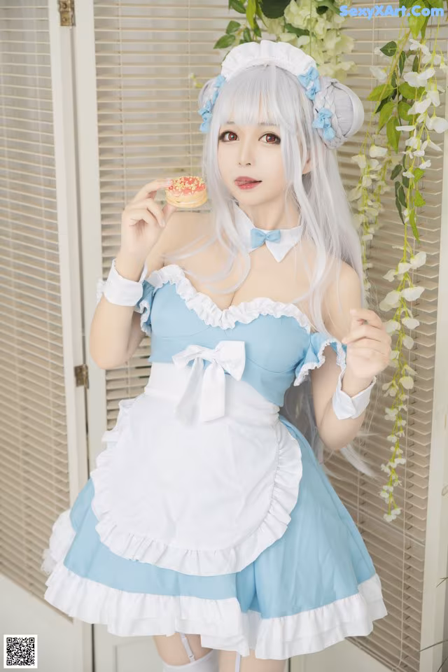 A woman in a blue and white dress holding a donut.
