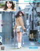 A woman standing on the side of a street next to a pole.