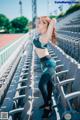 A woman in a sports bra top and leggings standing in a stadium.