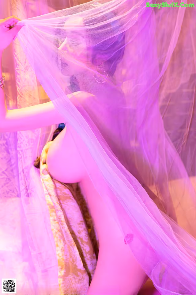 A woman in a pink dress with a veil over her head.