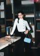 A woman standing in front of a desk holding a blue bag.