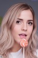 A woman holding a lollipop in front of her face.