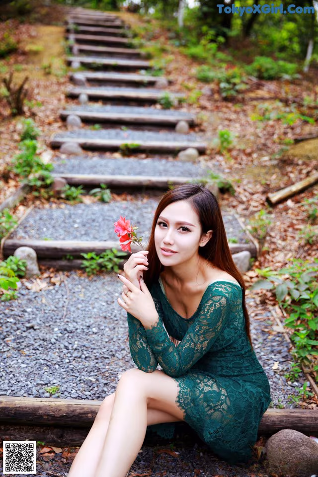 A woman in a green dress sitting on a train track.