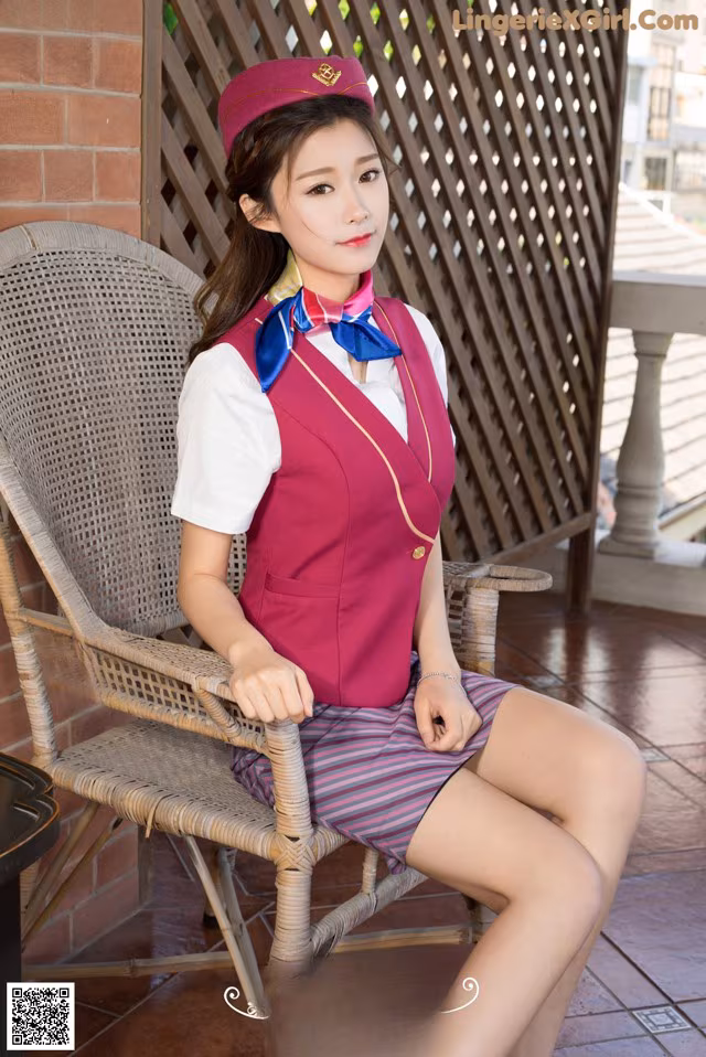 A woman in a pink uniform sitting on a chair.