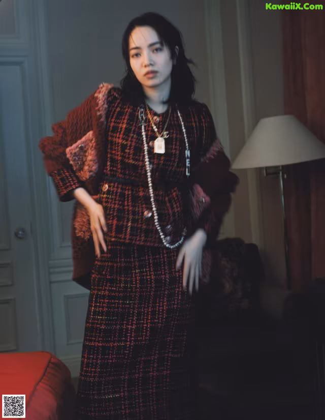 A woman standing in a room next to a bed.