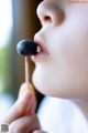 A young boy eating a blueberry on a stick.