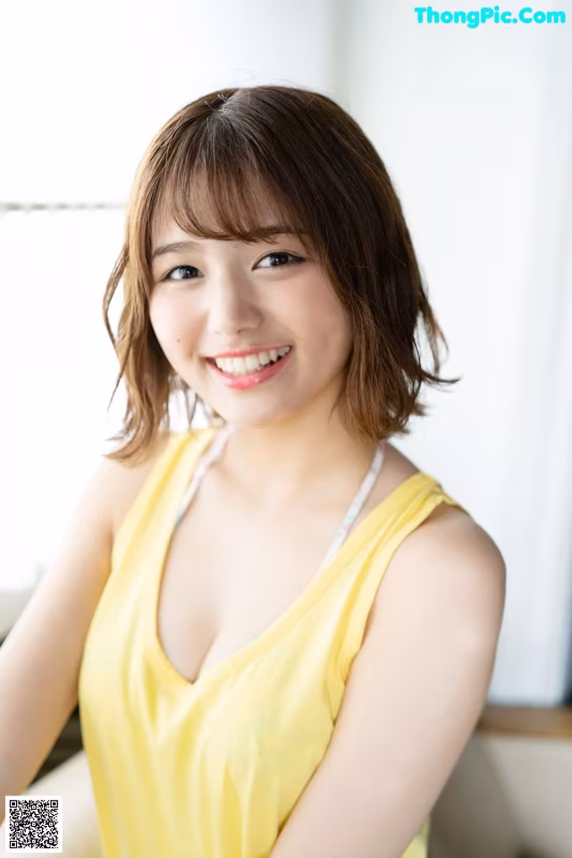 A woman in a yellow tank top posing for a picture.