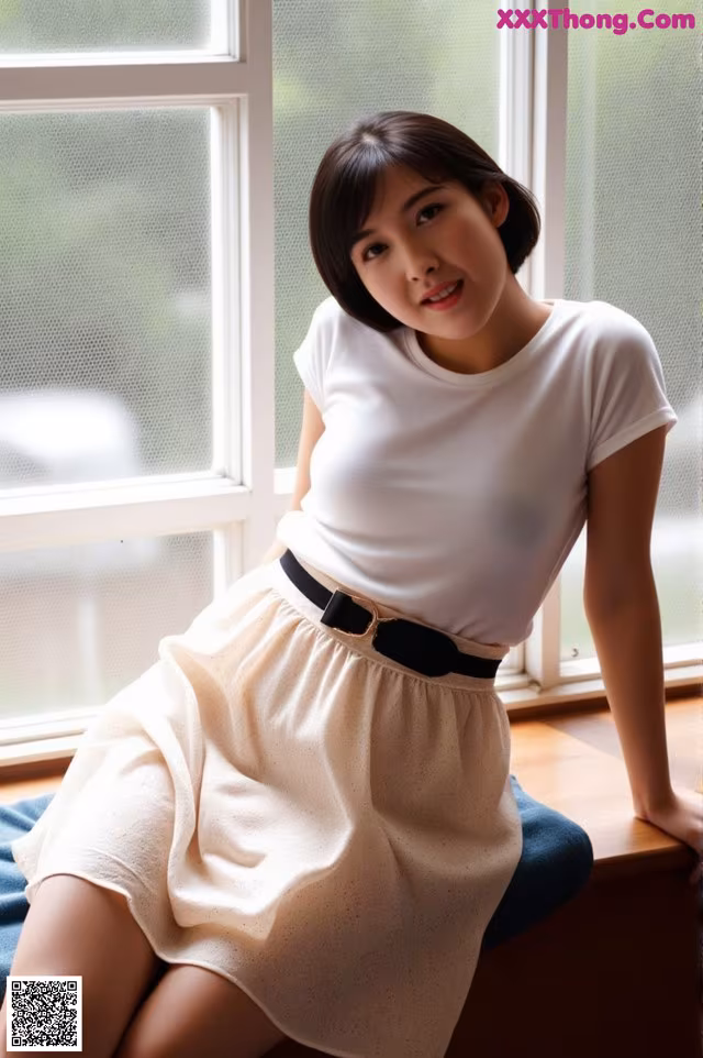 A woman sitting on a window sill wearing a white shirt and skirt.