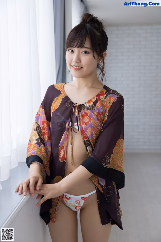 A woman in a bikini posing by a window.